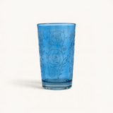 TUYYA Cadencia 4 oz Moroccan tea glass in vibrant blue glass with intricate embossed swirl and floral patterns.