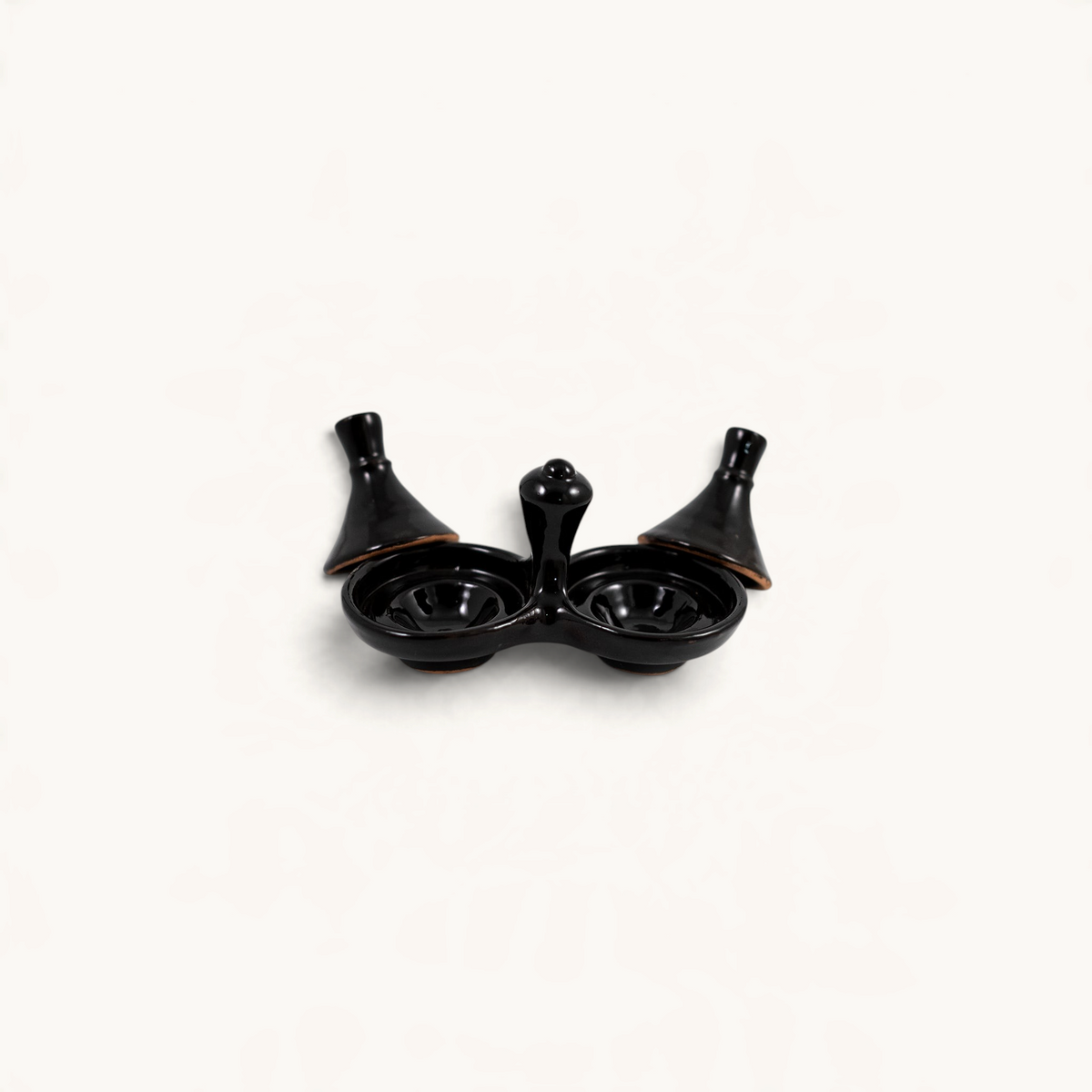 TUYYA handmade black ceramic salt and pepper tajine set for serving spices and condiments on a dining table.