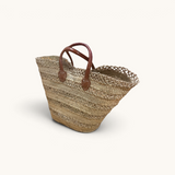 TUYYA handwoven Moroccan palm leaf basket with brown camel leather handles and horizontal etched line detailing.