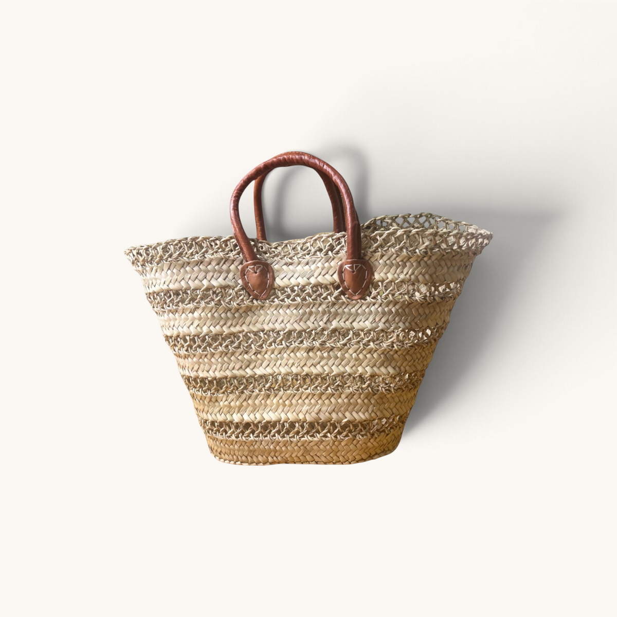TUYYA handwoven palm leaf basket with brown camel leather handles and horizontal etched lines for market or home use.