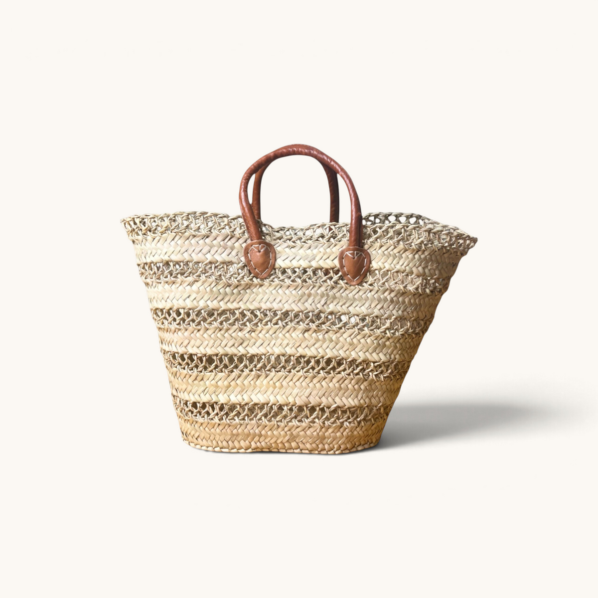 TUYYA handwoven Moroccan palm leaf basket with brown camel leather handles and horizontal etched line details.