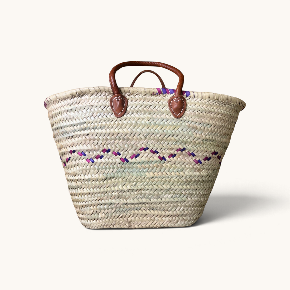 TUYYA Heydi large Moroccan wicker basket with purple and pink wavy geometric patterns and brown leather handles.