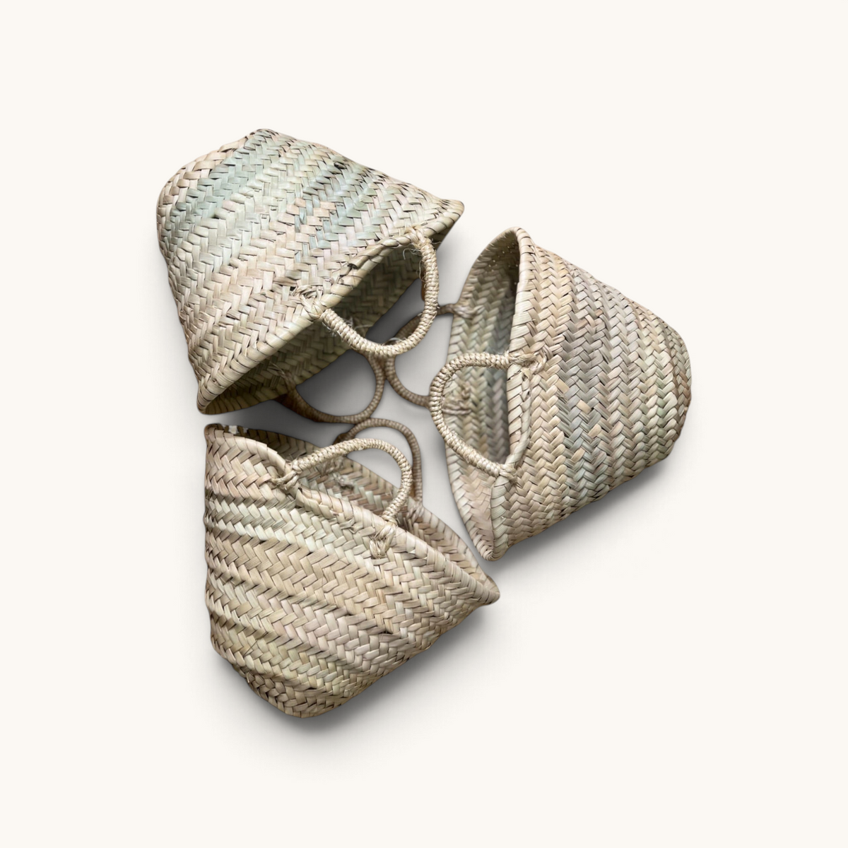 Three TUYYA small handwoven Moroccan wicker baskets with simple handles arranged in a circular pattern
