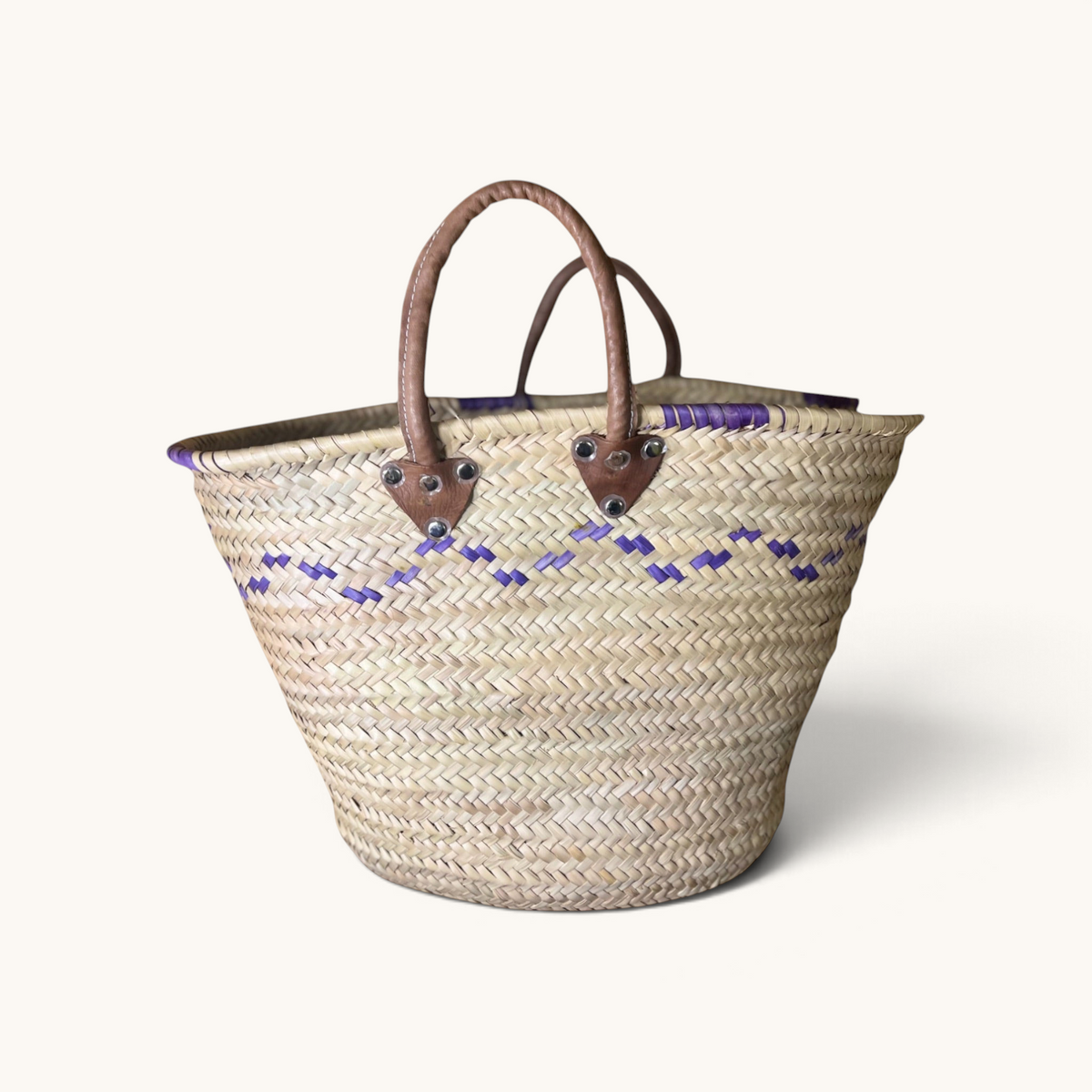 TUYYA Mimmi Moroccan wicker basket featuring purple wave patterns and sturdy brown leather handles with metal rivets.