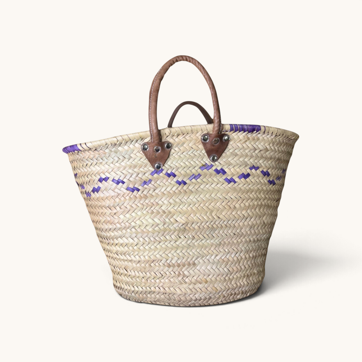 TUYYA Moroccan wicker basket with purple wave patterns and sturdy brown leather handles secured by metallic rivets.