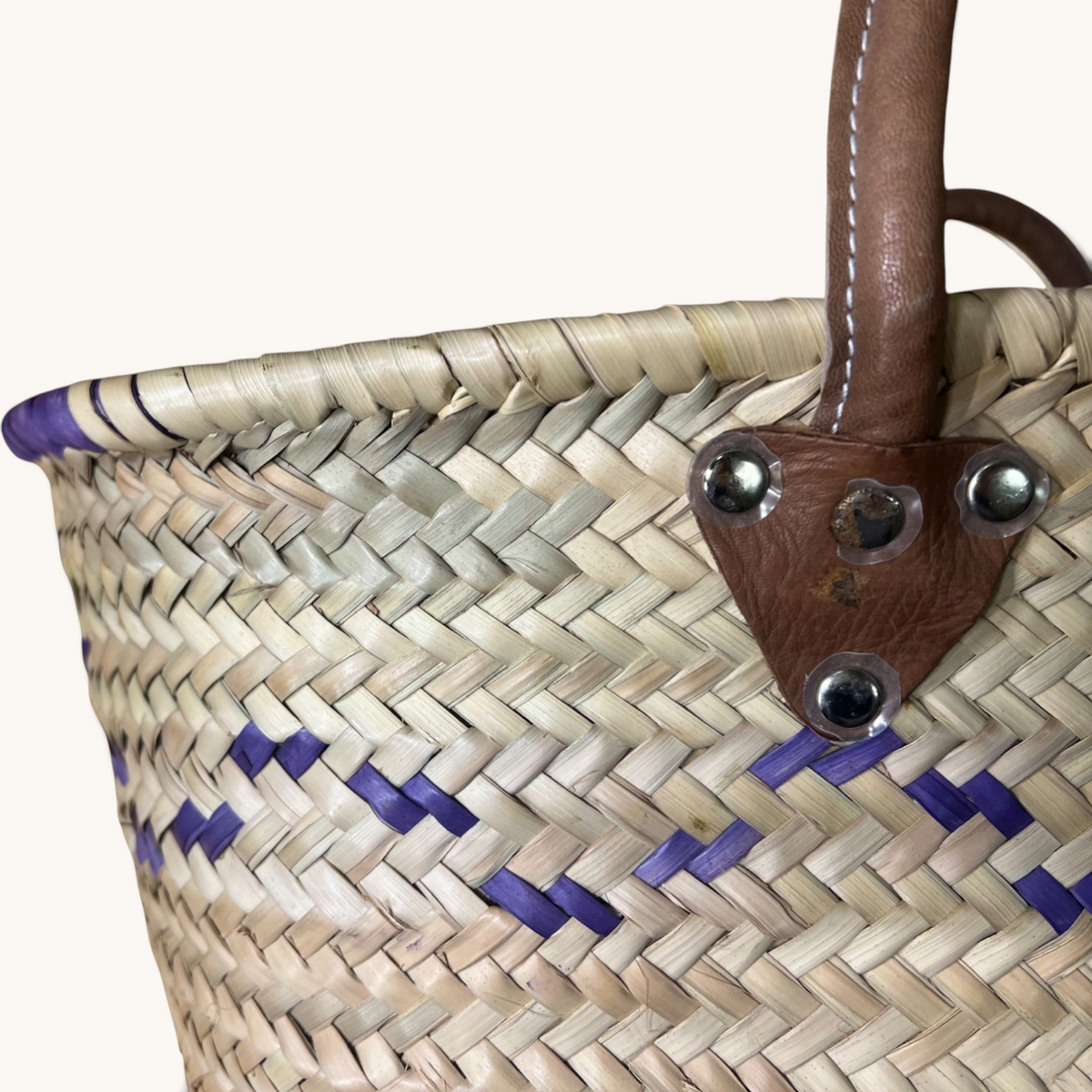 TUYYA Mimmi Moroccan wicker basket with purple wave patterns and brown leather handles secured by metallic rivets.