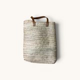 TUYYA Marrakech handwoven wicker tote bag with camel-colored leather handles and rivet details on a white background.
