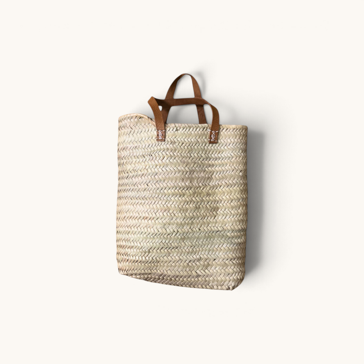 TUYYA Marrakech handwoven wicker tote bag with camel leather handles and rivet details on a white background