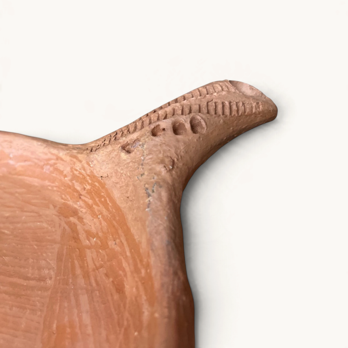 Close-up of a TUYYA handcrafted unglazed clay cooking pan handle with traditional textured Moroccan detailing.