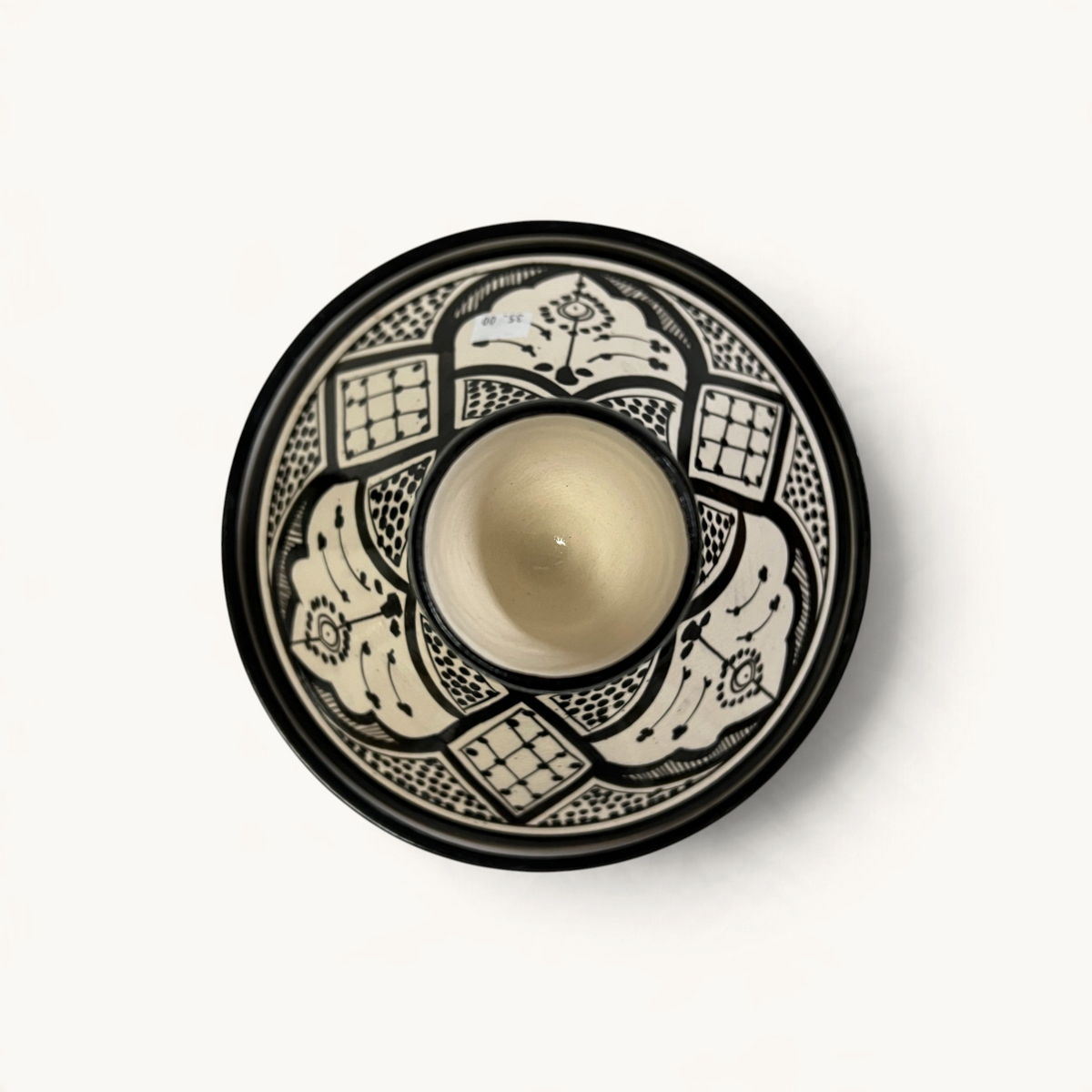 Tajine en céramique TUYYA noir et blanc avec motifs floraux marocains peints à la main, vue de dessus.