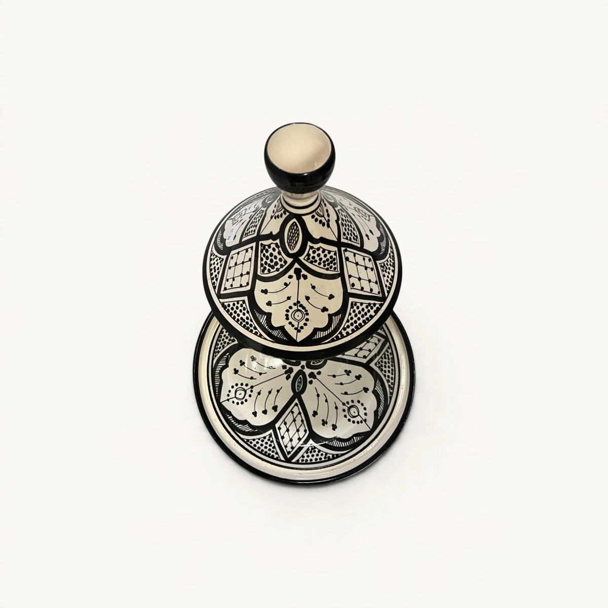 Tajine TUYYA en céramique noir et blanc avec motifs floraux marocains peints à la main, vue de dessus.