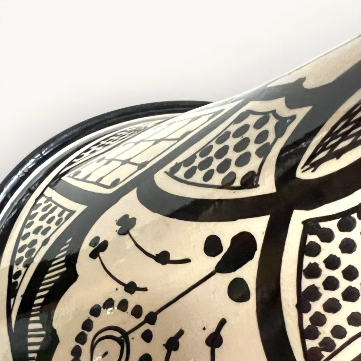 Gros plan sur un tajine en céramique TUYYA noir et blanc avec des motifs floraux marocains peints à la main.
