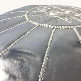 tuyya silver Moroccan vegan leather pouf with intricate hand-embroidered detailing on the top surface