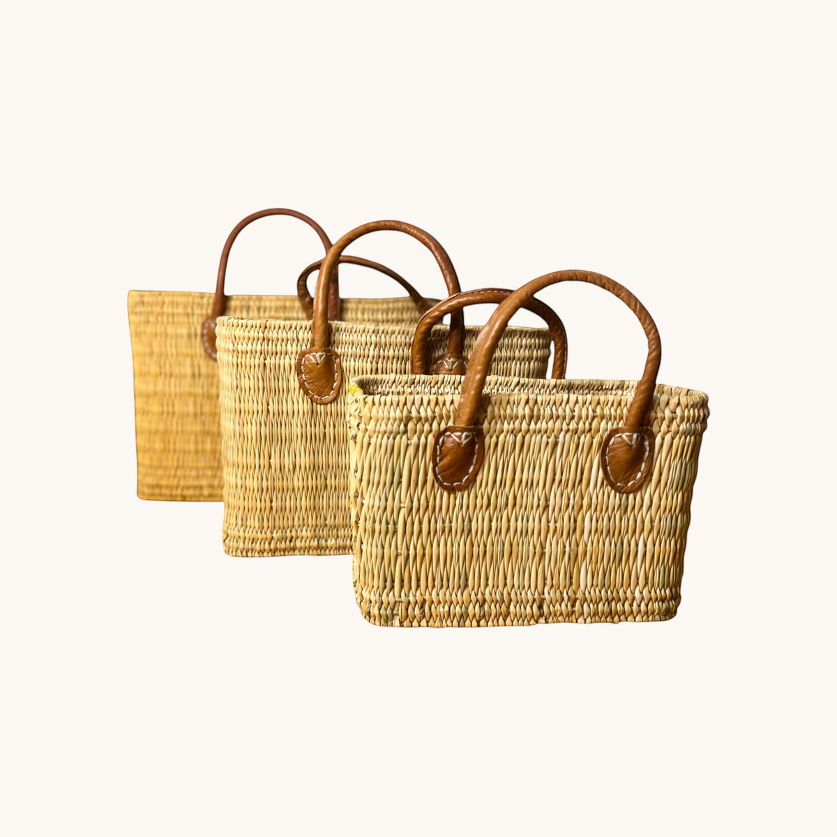 tuyya Yasmine structured Moroccan wicker baskets in three sizes with camel-colored leather handles and rivet details.