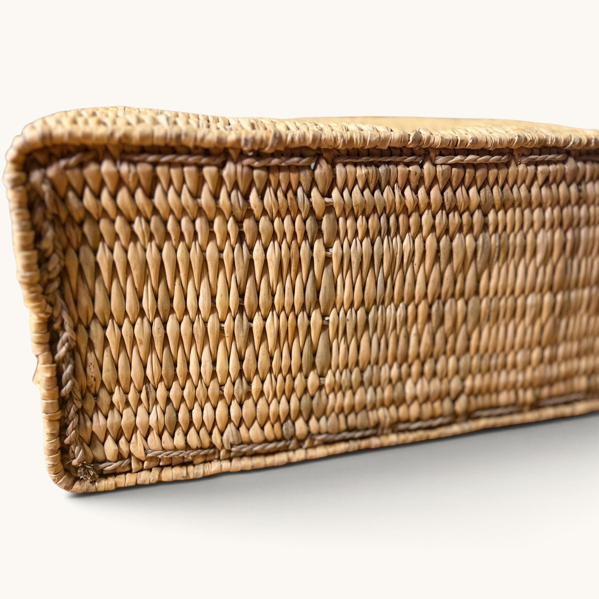 Close-up of the flat rectangular base of a tuyya Yasmine handwoven wicker basket with a rigid structured design.