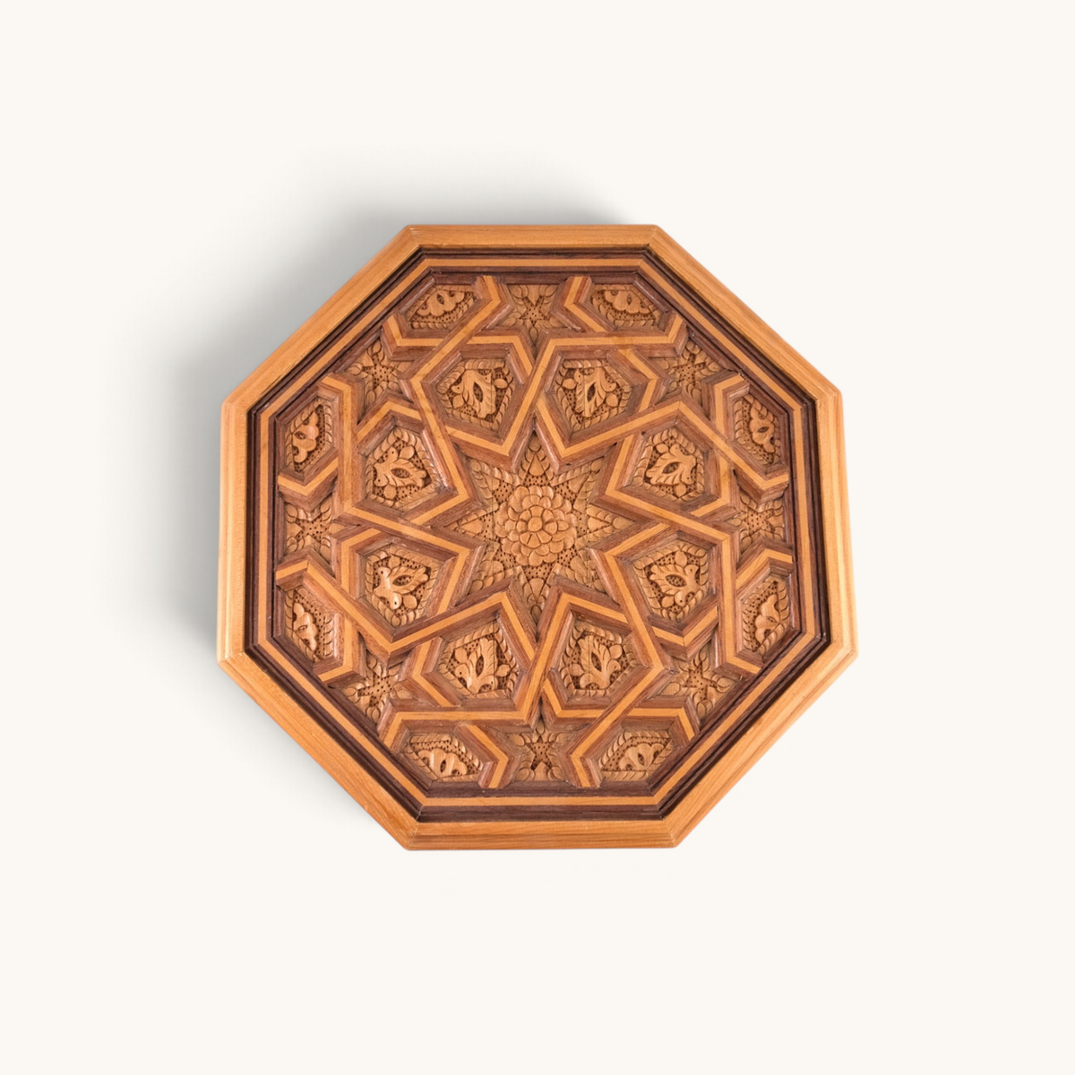 TUYYA octagonal side table featuring hand-carved floral patterns in samba, mahogany, and cedar wood with a glass top.